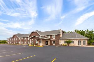 a large brick building with a parking lot at Days Inn & Suites by Wyndham Kaukauna WI in Kaukauna