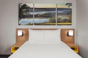 a bedroom with a bed and three paintings on the wall at Days Inn & Suites by Wyndham Kaukauna WI in Kaukauna +18 photos