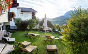 a patio with chairs and an umbrella on the grass at Panoramahotel Gürtl in Haus im Ennstal