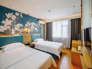 a hotel room with two beds and a painting on the wall at Jinjiang Inn Zibo People's Park Liuquan Road in Zibo +149 photos