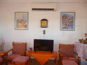 a living room with a tv and two chairs and a table at Golden Sun Rooms in Pyrgi Thermis