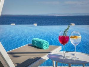 two glasses of wine on a table next to a pool at Apartment in Veli Lo inj by the Beach in Veli Lošinj