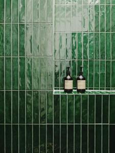 Un baño de azulejos verdes con dos botellas de jabón. en NOOK Stay am Checkpoint Charlie, en Berlín
