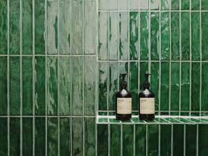 two bottles of wine on a shelf on a green tiled wall at NOOK Stay am Checkpoint Charlie in Berlin +29 photos