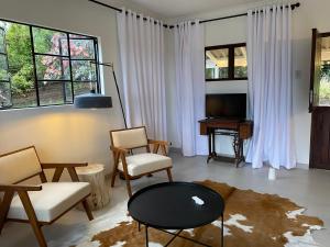 a living room with chairs and a tv and a table at Luxury modern farm cottage with sea view in Southbroom +42 photos