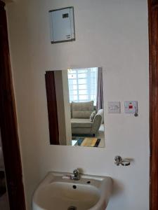 a bathroom mirror with a sink and a living room at Carlyle comfort home in Thika
