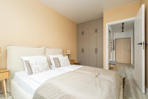 une chambre avec un grand lit blanc avec des oreillers blancs dans l'établissement Apartament Let's Sea z Basenem by BALTIC CLUB, à Gąski 20 autres photos