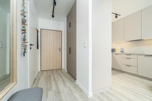 un couloir avec une porte menant à une cuisine avec des placards blancs dans l'établissement Apartament Let's Sea z Basenem by BALTIC CLUB, à Gąski
