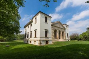 an old white building on a grassy field at Villa Pisani Bonetti in Lonigo