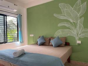 ein Schlafzimmer mit einem Bett mit einem Pflanzenwandbild an der Wand in der Unterkunft 12 Monks - Backpacker Resort in Arambol