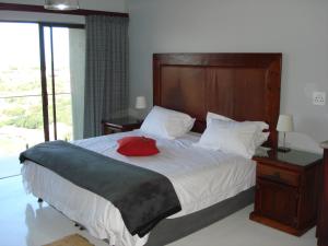 een slaapkamer met een groot bed met een rood kussen erop bij W21 in Groot Brak Rivier