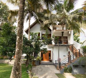 a house with palm trees in front of it at Mr & Mrs K's Villa- Kandy in Kandy
