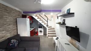 a living room with a couch and a staircase with a tv at Dunaflor Gemelo 1 in San Bartolomé de Tirajana