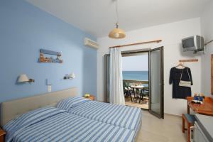 a bedroom with a bed and a view of the ocean at Flisvos Rooms in Plakias