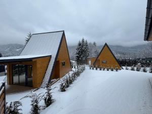 a couple of small wooden buildings in the snow at Nordic Dream Chalet in Buşteni