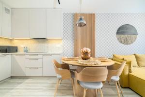 une cuisine et une salle à manger avec une table et des chaises dans l'établissement Apartament RIVIERA Let's Sea z Basenem by BALTIC CLUB, à Gąski