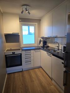 Una cocina con gabinetes blancos y una ventana. en Nice and spacious apartment in a quiet area, en Tromsø