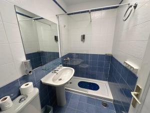 Un baño con azulejos azules, lavabo y espejo. en Dunaflor Gemelo 2, en San Bartolomé 5 fotos más
