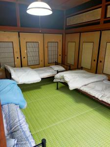 three beds in a room with a green carpet at 民泊いなほ館 in Shiso