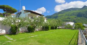 einen Garten vor einem Haus mit Bäumen und Bergen in der Unterkunft Appartamenti Ischia la Sentinella in Ischia