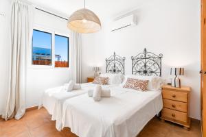 Un dormitorio blanco con dos camas y una ventana. en Villa Petre, en Cala'n Porter 25 fotos más