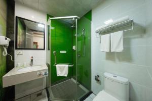 a green bathroom with a sink and a shower at Vatica Shanghai Pudong Dishui Lake Branch in Shanghai