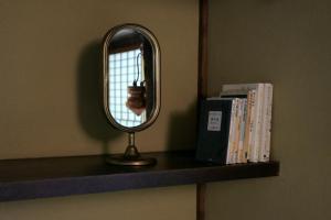a mirror sitting on top of a shelf with books at UTAHI  A 100-years-old Kyoto machiya in Kyoto +55 photos