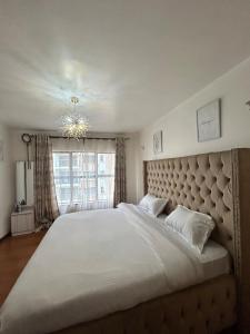 a large bed in a bedroom with a large window at The Alma Luxe Modern 1 bedroom Apartment in Ruaka