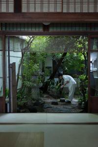 a man standing in a garden in a window at UTAHI  A 100-years-old Kyoto machiya in Kyoto +64 photos