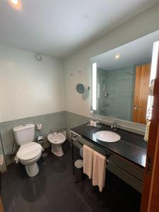 a bathroom with two sinks and a toilet and a mirror at Hotel Vila Galé Cerro Alagoa in Albufeira