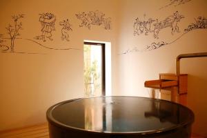 bañera en una habitación con dibujos en la pared en 城崎温泉お宿白山花まんだら, en Toyooka