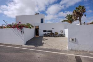 a white house with white walls and palm trees at Casa Alma by Escape Home in Tías