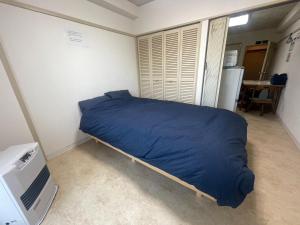 a small bedroom with a bed with a blue blanket at Ueda Building - Vacation STAY 8555 in Asahikawa