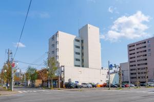 a large white building with cars parked in a parking lot at Ueda Building - Vacation STAY 11774 in Asahikawa