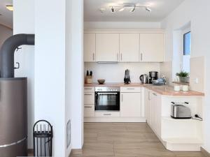 Una cocina con gabinetes blancos y una estufa. en Strandhafer, en Zingst