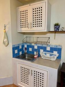 a kitchen with a sink and blue tiled wall at Ally home 12 23 in Thung Si Kan