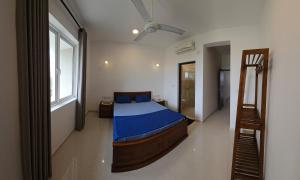 a bedroom with a bed with blue sheets and a window at Beach Front Apartment 1 in Bopitiya +13 photos