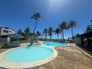 une grande piscine avec des palmiers en arrière-plan dans l'établissement Casa Privê Maragogi 26 - Pé na areia, à Maragogi