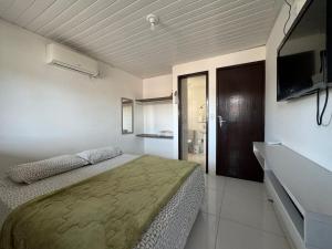 une chambre avec un lit et une télévision à écran plat dans l'établissement Casa Privê Maragogi 26 - Pé na areia, à Maragogi 27 autres photos