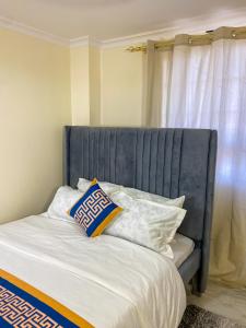 a bed with a blue headboard and pillows on it at Open Heaven Apartements in Ongata Rongai 