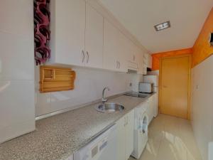 a kitchen with white cabinets and a sink at Apartamentos Terrasol BARCO 5 in Torre del Mar +6 photos