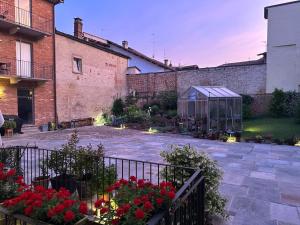 a garden with red flowers and a greenhouse at Recinto Nobili 2 - private parking vista cortile in Asti