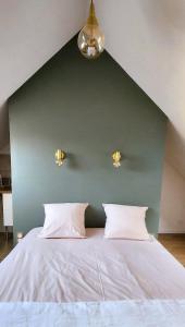a bed with two pillows in a room with a green wall at Les Hortensias Roses Duplex in Amiens