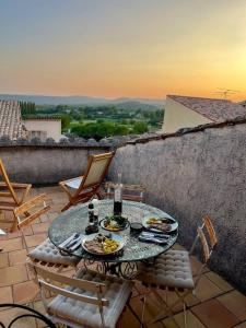 a glass table with plates of food on a patio at Maison Maples- Le charme provençal in Villecroze