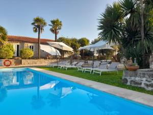 a pool with chairs and umbrellas next to a house at Quinta de Castelhão in Barcelos