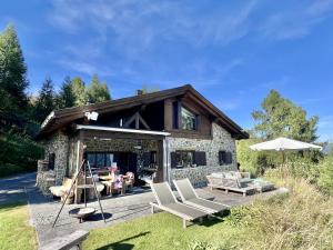 a stone house with two chairs and an umbrella at Bergchalet Flöna in Scuol