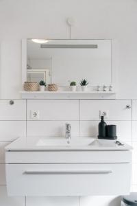 un bagno bianco con lavandino e specchio di FeriendomizilaufderZollernalb ad Albstadt