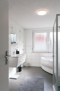 un bagno bianco con vasca e lavandino di FeriendomizilaufderZollernalb ad Albstadt Altre 35 foto