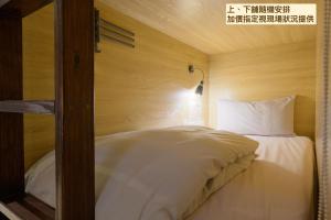 a bed with white sheets and a lamp in a room at Work Inn 101 慕誠青年旅館 in Taipei