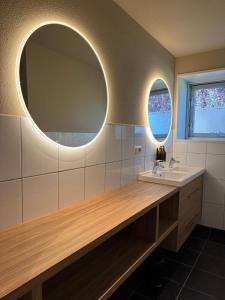 a bathroom with a sink and two round mirrors at Stijlvol & ruim relax vakantiehuis 'De Meierij' in Schijndel